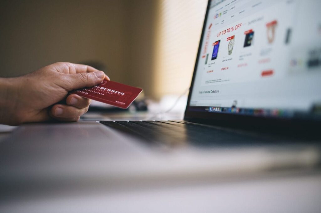 Person holding red credit card while shopping online during Black Friday deals on a laptop screen.